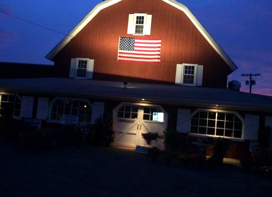 The Red Barn at dusk with the American flag on the gable