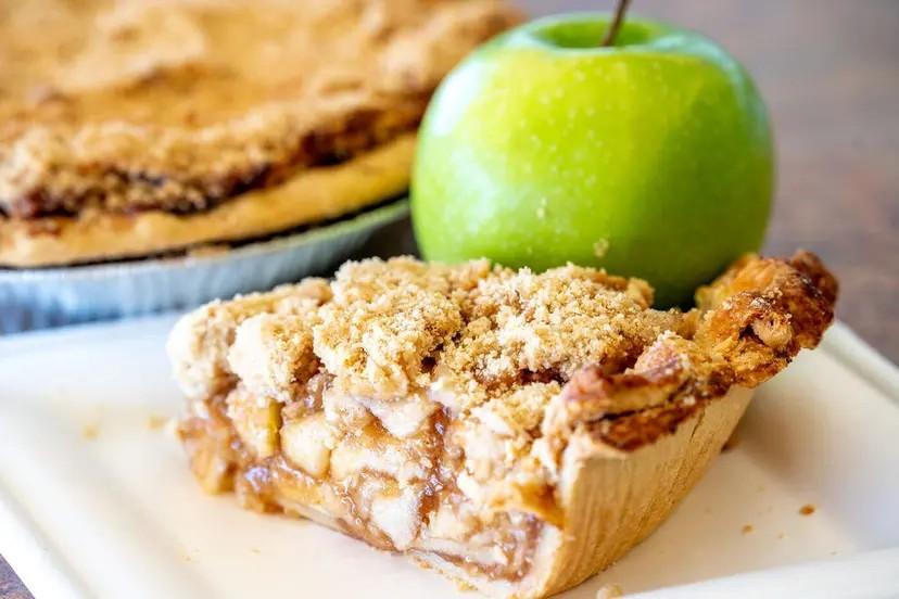 A slice of apple crumb pie with a Granny Smith apple